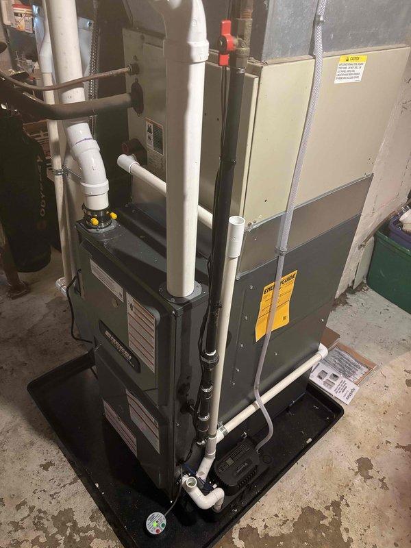 Successfully completed furnace installation in basement utility area. Installed new residential heating system with proper ductwork connections, positioning unit on protective drain pan platform alongside existing water heater. Established all necessary PVC condensate drain lines and venting, integrated system with overhead ductwork, and verified proper clearances and connections between equipment. All work completed to manufacturer specifications with system tested and operational.