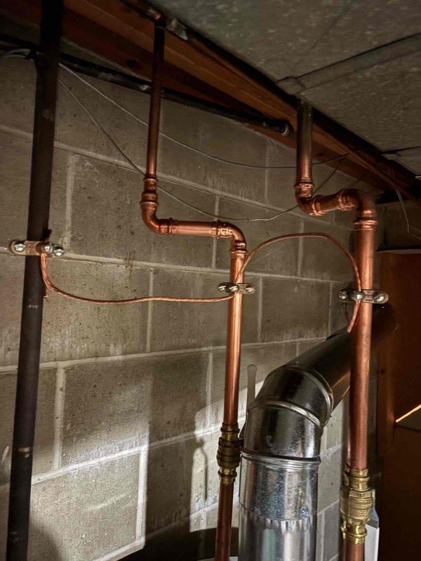 Responded to final inspection correction for missing electrical bonding on water heater and water meter. Installed proper bonding jumpers on copper water lines using code-compliant grounding clamps and copper wire to ensure electrical continuity and safety per municipal requirements. System now meets electrical code standards for metallic water piping bonding.