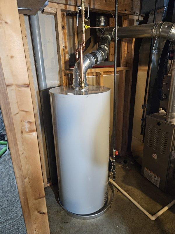 Completed installation of Bradford White 40-gallon automatic storage water heater, model BUC240S6N, with 40,000 BTU/h input capacity in residential utility room. Unit was properly positioned, all supply and discharge piping connections were secured, exhaust venting was installed to manufacturer specifications, and gas line connections were completed and pressure-tested for safe operation. Water heater was installed adjacent to existing furnace system within exposed framing area, with all work meeting ANSI Z21 certification standards and local code requirements for proper clearances and ventilation.
