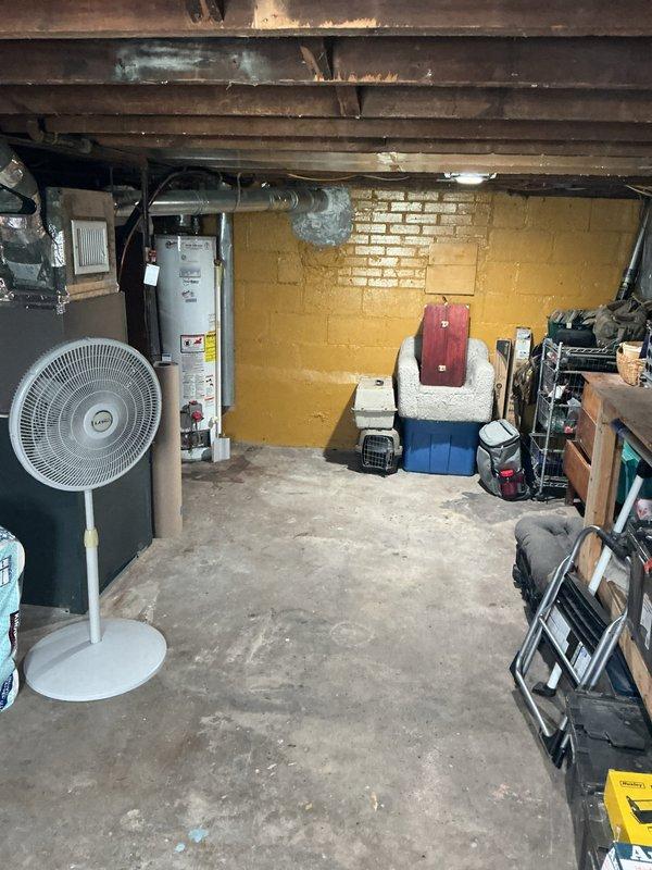 Responded to water heater leak in single family residence basement. Upon arrival, inspected white tank-style water heater mounted against painted brick wall and documented existing conditions including plumbing connections, surrounding utility area, and potential water damage to concrete floor. Assessed unit age, manufacturer information, and leak source to determine appropriate repair or replacement recommendations for homeowner.