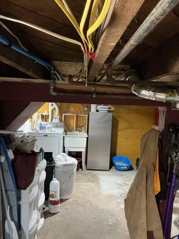 Responded to water heater leak in single family residence basement. Upon arrival, inspected white tank-style water heater mounted against painted brick wall and documented existing conditions including plumbing connections, surrounding utility area, and potential water damage to concrete floor. Assessed unit age, manufacturer information, and leak source to determine appropriate repair or replacement recommendations for homeowner.