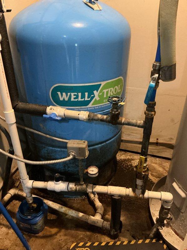 Responded to service call for condensation on pipes connected to furnace and water heater system. Upon inspection, identified condensation forming on cold water supply lines near well pressure tank and water treatment system. Examined WELL-X-TROL pressure tank, associated PVC plumbing connections, and surrounding piping network. Noted moisture accumulation on uninsulated cold water pipes due to temperature differential between cold supply lines and warm ambient air in utility area. Verified all plumbing connections for leaks and confirmed condensation was environmental rather than a plumbing failure. Documented existing water staining on floor near equipment base and observed some corrosion on older metal pipe fittings. Recommended additional pipe insulation on exposed cold water lines to prevent future condensation issues.
