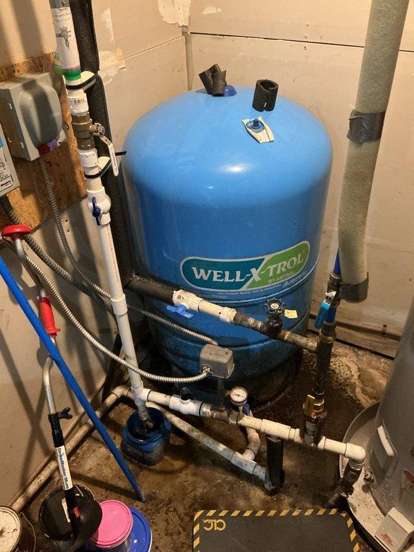 Responded to service call for condensation on pipes connected to furnace and water heater system. Upon inspection, identified condensation forming on cold water supply lines near well pressure tank and water treatment system. Examined WELL-X-TROL pressure tank, associated PVC plumbing connections, and surrounding piping network. Noted moisture accumulation on uninsulated cold water pipes due to temperature differential between cold supply lines and warm ambient air in utility area. Verified all plumbing connections for leaks and confirmed condensation was environmental rather than a plumbing failure. Documented existing water staining on floor near equipment base and observed some corrosion on older metal pipe fittings. Recommended additional pipe insulation on exposed cold water lines to prevent future condensation issues.