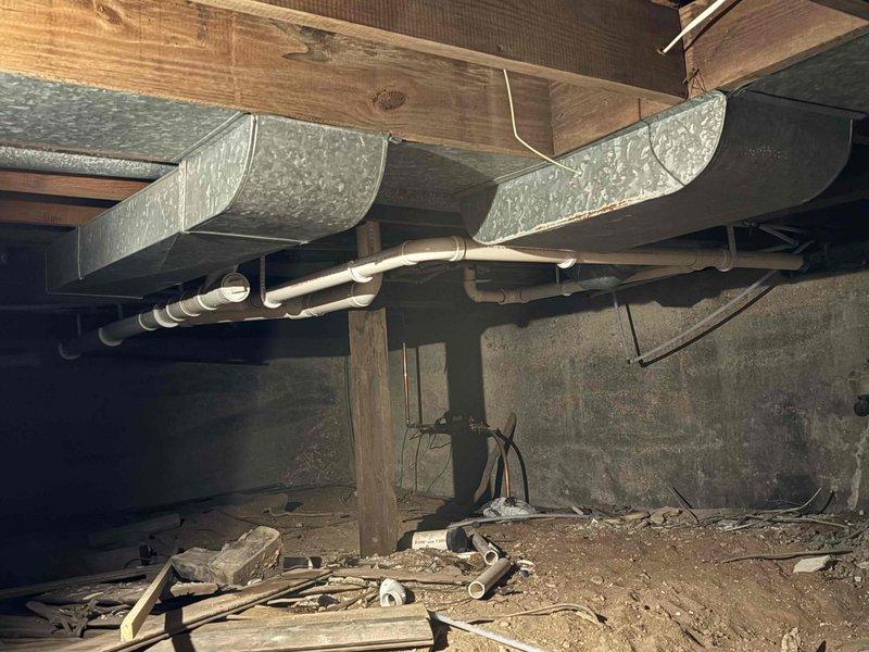 Completed rough-in plumbing installation in crawl space for new bathroom fixtures including toilet, vanity, and shower. Installed PVC drain lines and water supply lines beneath floor joists, properly securing all pipes with mounting brackets and straps to wooden framing. All rough-in work positioned to accommodate future fixture installation and inspected for proper slope and venting requirements.