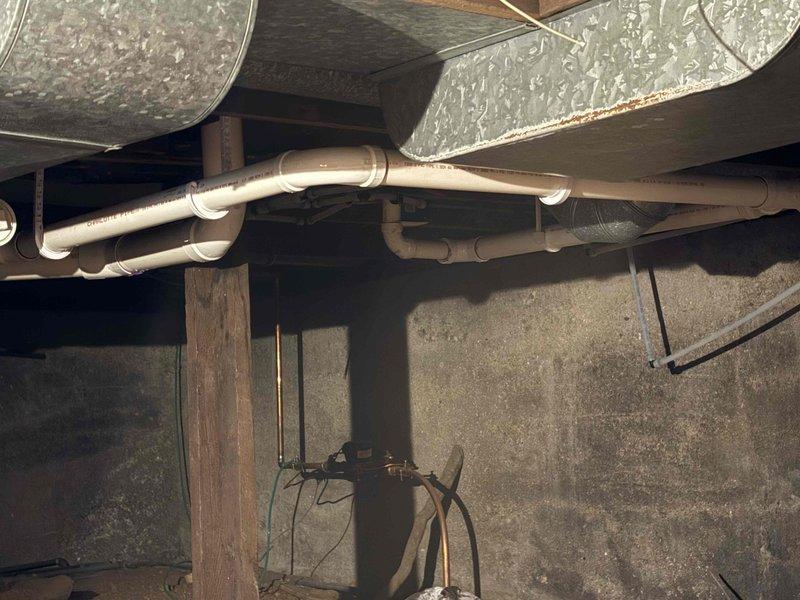Completed rough-in plumbing installation in crawl space for new bathroom fixtures including toilet, vanity, and shower. Installed PVC drain lines and water supply lines beneath floor joists, properly securing all pipes with mounting brackets and straps to wooden framing. All rough-in work positioned to accommodate future fixture installation and inspected for proper slope and venting requirements.