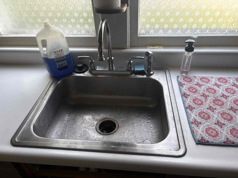 Responded to emergency call for active water leak at residential property. Upon arrival and inspection, located source of leak at kitchen sink P-trap assembly beneath cabinet. Found loose slip-joint connection on PVC P-trap allowing water to escape during sink usage. Tightened slip-joint fittings on P-trap assembly to manufacturer specifications and tested system by running water through sink drain. Verified no additional leaks present and confirmed all plumbing connections secure and functioning properly.
