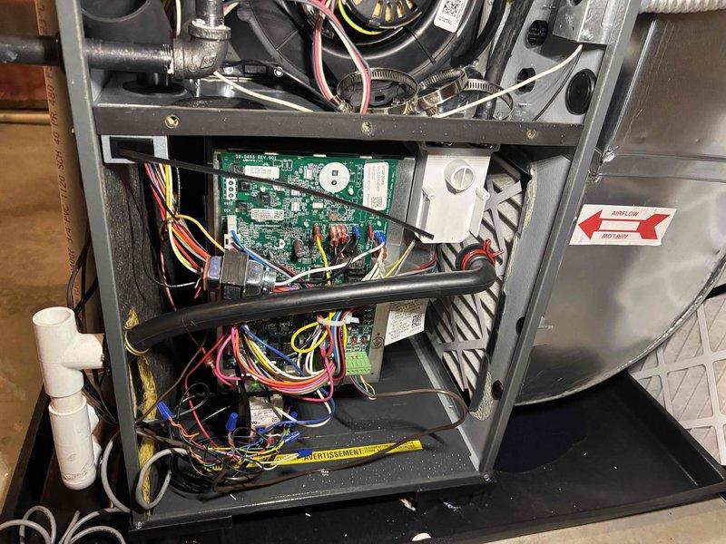 # No Heat Call - Furnace System Inspection and Diagnosis

Responded to no heat call with reported blank thermostat and water accumulation in drain pan. Upon arrival, confirmed HVAC system was completely non-operational with no blower function.

Removed access panels and performed comprehensive visual inspection of furnace cabinet interior. Examined all major components including blower motor assembly, control board, wiring harnesses, and condensate management system. 

Inspected green integrated furnace control board for signs of failure, including burned components, tripped safety circuits, or loose connections. Verified all wire harnesses and connectors at control board for proper seating and continuity. Checked power supply to unit and control voltage circuits.

Examined white condensate pump assembly and associated drainage system. Confirmed presence of standing water in condensate pan, indicating potential pump failure or drain line blockage. Traced white PVC condensate drain pipi