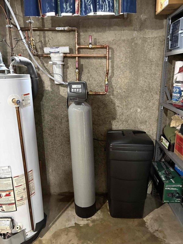 Completed installation of SWS1-30 water softener system in basement utility area. Installed beige cylindrical softener tank with digital control head, connected brine tank for salt storage, and integrated system with existing copper plumbing infrastructure using appropriate fittings and shut-off valves. Routed supply lines to interface with water heater, ensuring proper flow configuration and system functionality. Installation time totaled 4 hours with all components tested and operational upon completion.