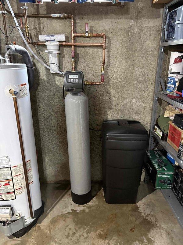 Completed installation of SWS1-30 water softener system in basement utility area. Installed beige cylindrical softener tank with digital control head, connected brine tank for salt storage, and integrated system with existing copper plumbing infrastructure using appropriate fittings and shut-off valves. Routed supply lines to interface with water heater, ensuring proper flow configuration and system functionality. Installation time totaled 4 hours with all components tested and operational upon completion.
