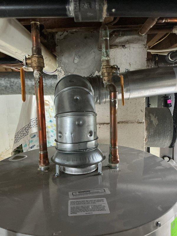 Responded to service call for water heater producing loud screeching sound with water present in drain pan. Upon inspection, found 6-year-old Bradford White water heater in basement utility area with visible water accumulation in collection tray. Identified source of screeching noise as failing temperature and pressure relief valve. Inspected all plumbing connections, copper supply lines, and drain pan for signs of active leaking or corrosion. Documented current condition of unit with photographs showing mechanical installation, City of Lansing mechanical inspection approval sticker dated 7-16-2020, and overall system configuration. Advised customer of findings and recommended immediate replacement of faulty T&P relief valve to eliminate noise and prevent potential safety hazard.