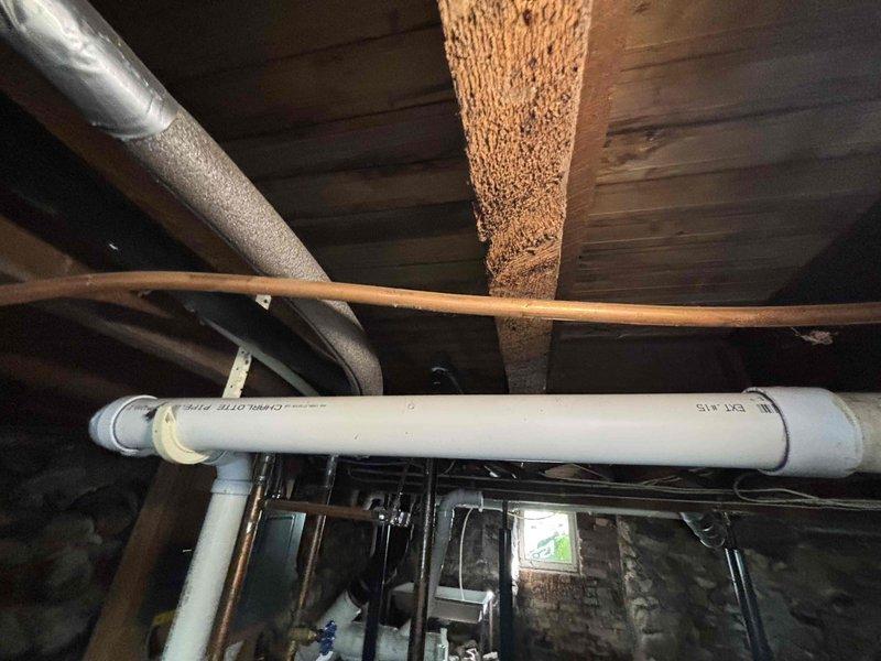 Responded to service call for 10-year-old Bradford White standard tank water heater in single family residence. Performed comprehensive diagnostic inspection of unit and surrounding mechanical systems in basement utility area. Evaluated water heater operation, inspected gas connections, venting system, and plumbing infrastructure including copper supply lines and PVC discharge piping. Assessed overall condition of installation including proximity to HVAC ductwork and structural support beams. Documented equipment status and utility space conditions with photographic evidence for service records.