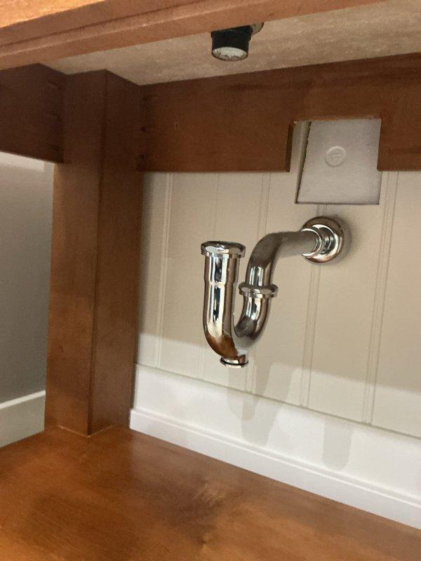 Responded to report of broken pipe beneath bathroom vanity sink. Upon arrival, inspected plumbing connections under vessel sink and determined P-trap and drain assembly were secure with no active leaks detected. Chrome P-trap showed proper installation with tight connections at slip joints. Wall-mounted faucet and drain system functioning normally with no visible water damage to cabinet interior or surrounding areas. Verified all plumbing fixtures operational and leak-free at time of inspection.