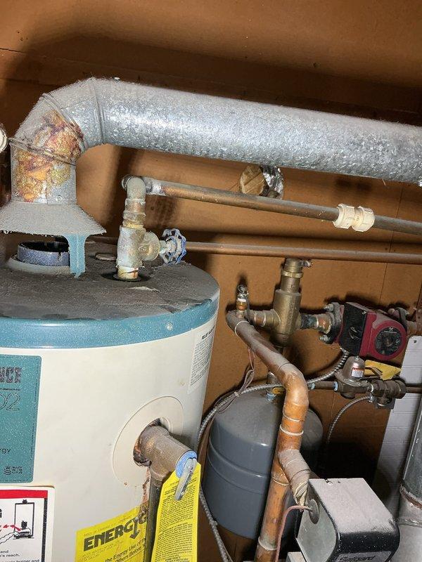 Performed comprehensive inspection of 27-year-old Reliant water heater and associated plumbing systems. Documented multiple safety and code compliance concerns including significant corrosion around water supply connections and heat source area, absence of required sediment trap on gas line, and improper shared exhaust venting configuration between water heater and boiler system. Photographed all deficiencies for client review and future remediation planning.