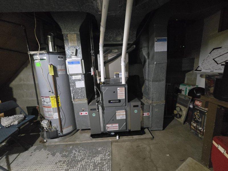 Successfully completed furnace installation in basement mechanical room. Installed new gray furnace unit with proper PVC venting system routed to exterior, positioned centrally alongside existing water heater and additional HVAC components. Verified all electrical connections, gas line hookups, and condensate drainage are properly configured and operational. System tested and confirmed functioning within manufacturer specifications.
