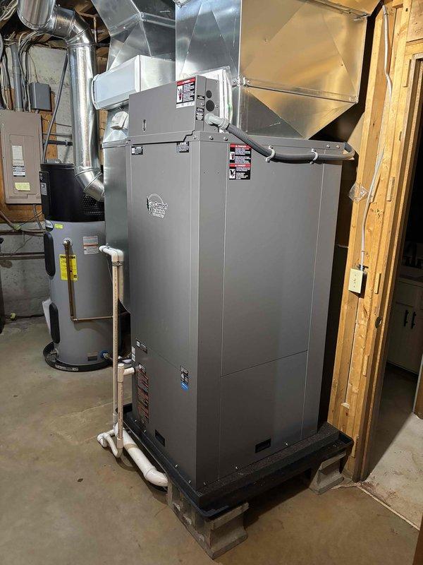 Completed full geothermal HVAC system installation in residential basement utility room. Installed and positioned geothermal heat pump unit on wooden pallet with proper elevation, connected metallic supply and return ductwork to existing distribution system, and integrated stainless steel flue piping with 90-degree transitions extending to exterior termination point. Established all necessary copper piping connections with white insulation wrapping, installed PVC condensate drain lines, and connected water heater integration with pressure relief valves and circulation components. Secured all mechanical equipment to code specifications, verified proper electrical connections to panel box, ensured all manufacturer labels and safety warnings remained visible, and conducted system pressure testing. Installation completed with all components operational and ready for commissioning.