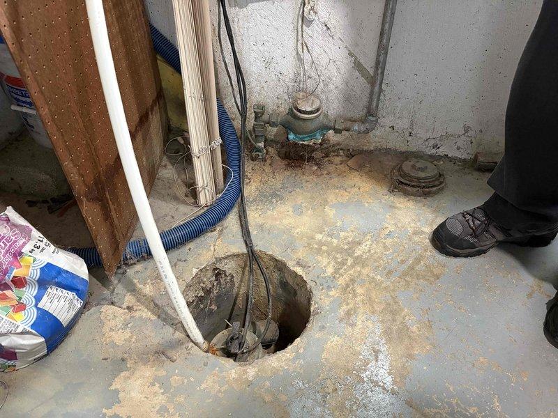 Responded to service call for sump pump that was continuously running. Upon inspection, found sump pit with visible water staining and moisture around the basin area, indicating frequent cycling or discharge issues. Evaluated sump pump operation, checked float switch mechanism, and assessed discharge line routing from basement to exterior-mounted junction box. Resolved running condition by addressing float switch positioning and verified proper pump cycling and automatic shut-off functionality.