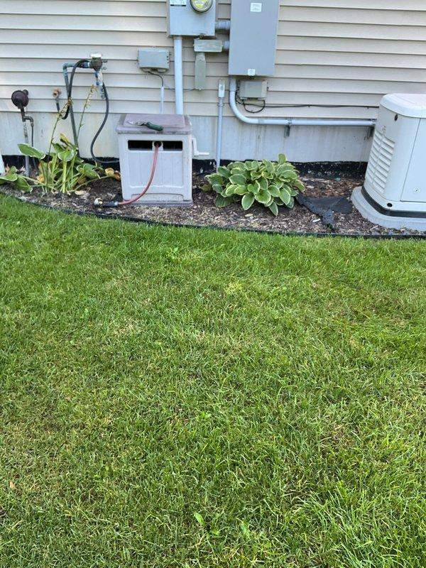 Conducted on-site evaluation of back-pitched plumbing line running from residence to septic tank system. Documented existing conditions through photographic survey of property, including septic system access point location in lawn area and exterior plumbing penetrations at foundation level. Prepared comprehensive project estimate for correction of improper pipe slope to ensure proper drainage flow toward septic tank and prevent future system backup issues.