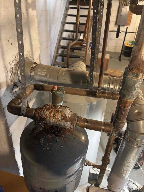 Responded to boiler system concern regarding corrosion near expansion tank. Upon inspection, discovered extensive rust and oxidation on horizontal piping sections connected to the pressure vessel, with heavy deterioration on pipe fittings and joints showing advanced corrosion requiring attention. Documented conditions with photographs for customer records and future reference.