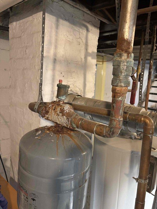 Responded to boiler system concern regarding corrosion near expansion tank. Upon inspection, discovered extensive rust and oxidation on horizontal piping sections connected to the pressure vessel, with heavy deterioration on pipe fittings and joints showing advanced corrosion requiring attention. Documented conditions with photographs for customer records and future reference.