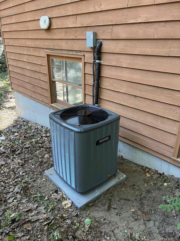 Completed full HVAC system installation including new furnace unit in basement mechanical room and outdoor condensing unit. Furnace installed against foundation wall with proper ductwork connections to existing metallic supply plenum and white PVC venting routed through ceiling area. Exterior AC unit positioned on concrete pad with refrigerant line set and electrical disconnect mounted to exterior wall, conduit run completed, and all connections properly secured and tested for operation.