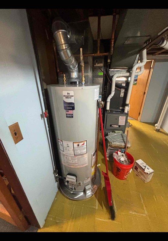 Completed full drain repipe in basement, removing deteriorated cast iron and copper drain lines from concrete floor elevation through subfloor and replacing with PVC drainage system. Removed and replaced 13-year-old water heater with new Bradford White 50-gallon natural draft natural gas unit, including proper venting and copper supply connections. All work completed in one day with 10-year workmanship guarantee provided on installation.