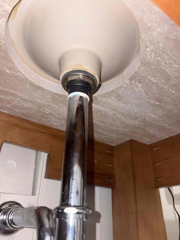 Completed replacement of bathroom sink drain assembly including P-trap and tailpiece connections. Removed existing worn components and installed new chrome tailpiece with black plastic P-trap assembly, ensuring proper alignment and secure coupling nut connections to prevent leaks.