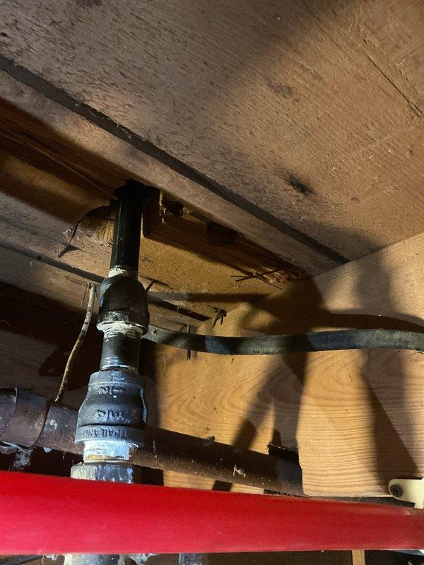 Completed QUOTR-quoted repair work on plumbing system. Installed brass fittings and components at floor level near baseboard area. Addressed corroded black drain pipe section visible in crawl space or subfloor area, secured with metal clamps to floor joists. Work completed without issues. Technician to return at later date to install shut-off valve as planned continuation of this repair. Total work time approximately 2 hours.