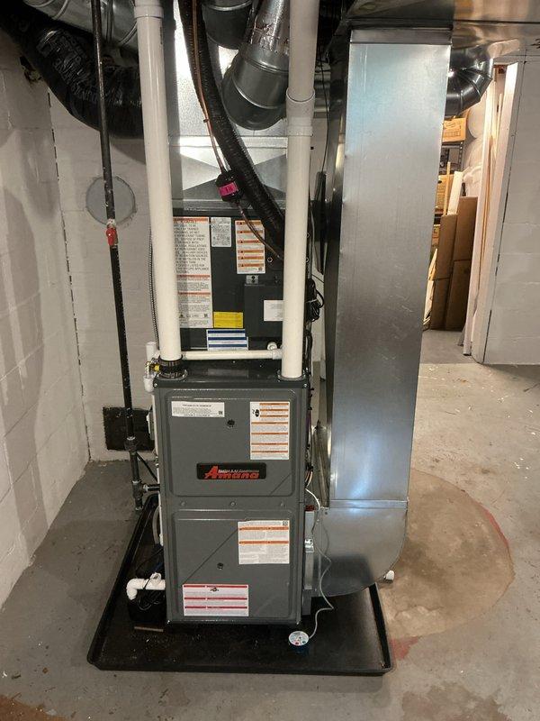 Completed full installation of Amana furnace and air conditioning system in residential basement. Unit was properly mounted on drip pan with PVC intake/exhaust venting installed vertically, ductwork connections secured, and electrical components wired according to specifications. System was tested and left operational with all safety labels and manufacturer documentation in place.