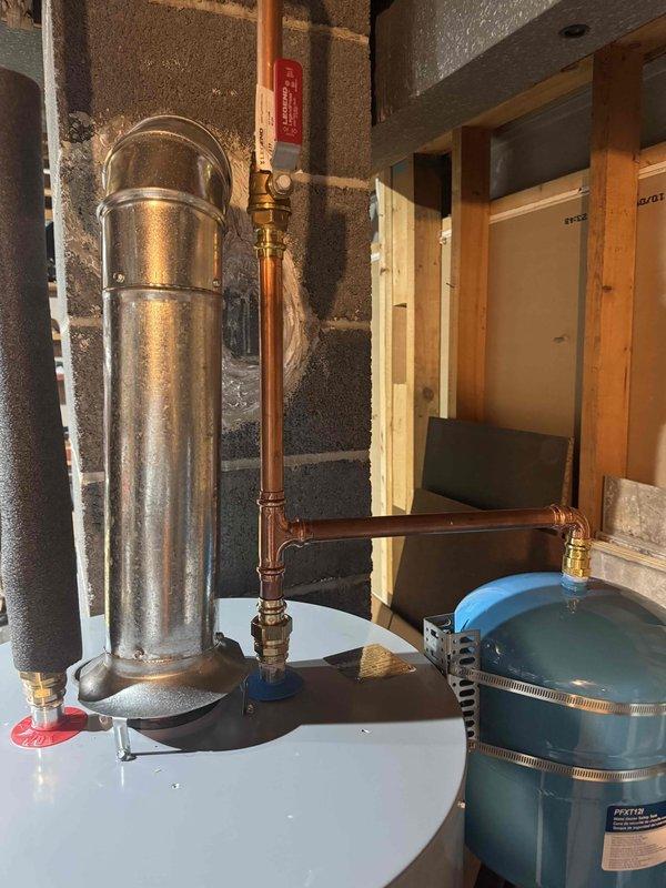 Installed 40-gallon short natural gas water heater as warranty replacement in unfinished basement utility area. Connected copper supply lines with brass fittings, installed expansion tank with proper mounting hardware, and verified all plumbing connections for leaks. Installed exhaust flue pipe, tested gas connections, and confirmed unit operation per manufacturer specifications.