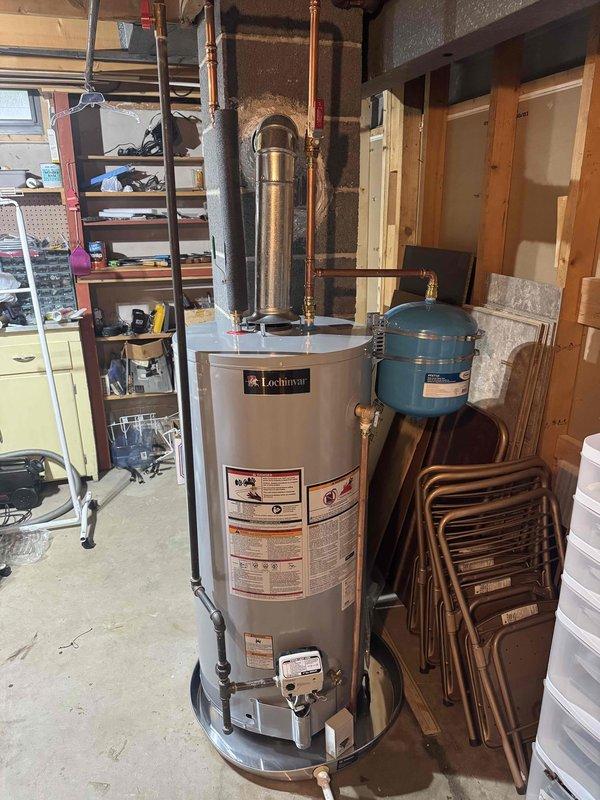 Installed 40-gallon short natural gas water heater as warranty replacement in unfinished basement utility area. Connected copper supply lines with brass fittings, installed expansion tank with proper mounting hardware, and verified all plumbing connections for leaks. Installed exhaust flue pipe, tested gas connections, and confirmed unit operation per manufacturer specifications.