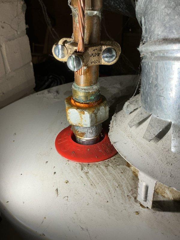 Responded to no hot water complaint on tank-style water heater. Upon arrival, accessed unit through rear entrance as requested. Inspected water heater installation in utility space, noting aged plumbing components with visible corrosion and patina on brass valve assembly and copper piping connections. Documented existing conditions including tarnished brass fittings, soldered copper joints, and overall system age indicators. Assessed valve operation, supply connections, and distribution piping in confined mechanical space. Customer is active plan member and was prioritized for service response.