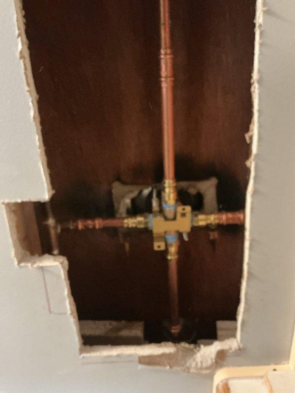 Responded to plumbing leak issue and performed diagnostic inspection of water supply system. Opened wall cavity to access copper piping, brass manifold assembly, and shutoff valves to identify source of leak. Technician to return for completion of repair work and wall restoration.