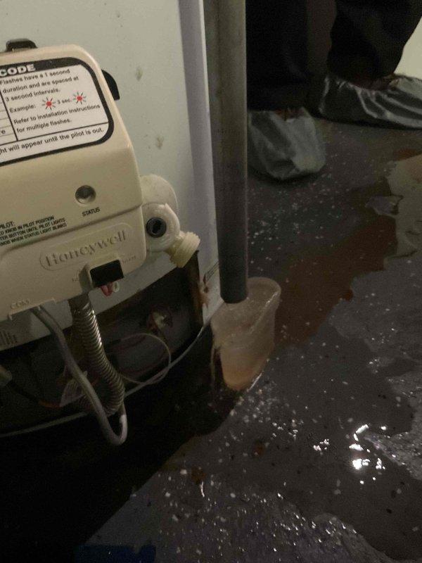 Responded to water heater leak with inconsistent temperature distribution throughout home. Upon arrival, found active water pooling on basement floor beneath unit and confirmed leak at water heater connections. Inspected Honeywell unit over 10 years old, documented water damage to surrounding area, and assessed flex line connections and valve fittings for failure points. Photographed leak source and standing water conditions for documentation purposes.