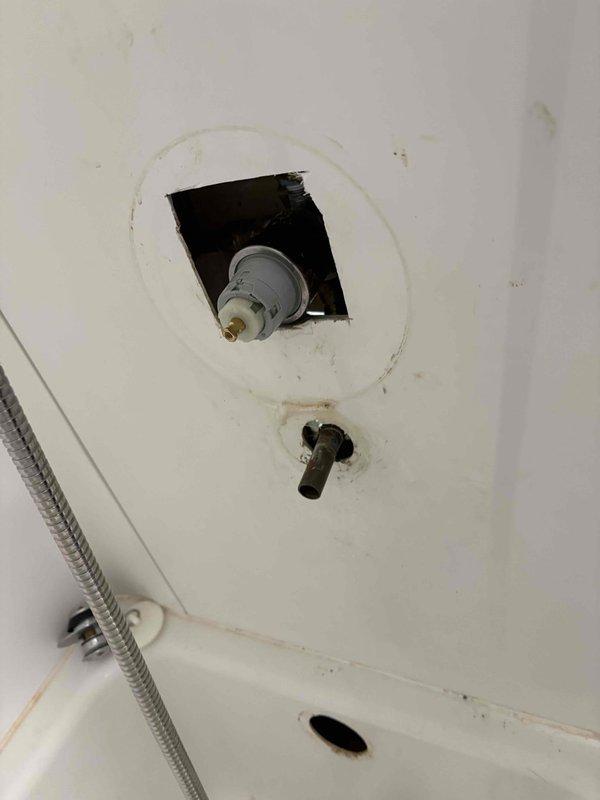 Completed installation of new shower trim kit with replacement valve cartridge and tub drain assembly. Accessed plumbing through existing wall opening, removed old worn components, installed new chrome-finished trim with brass valve stem, and replaced deteriorated tub drain hardware to restore full functionality to the bathing fixture.