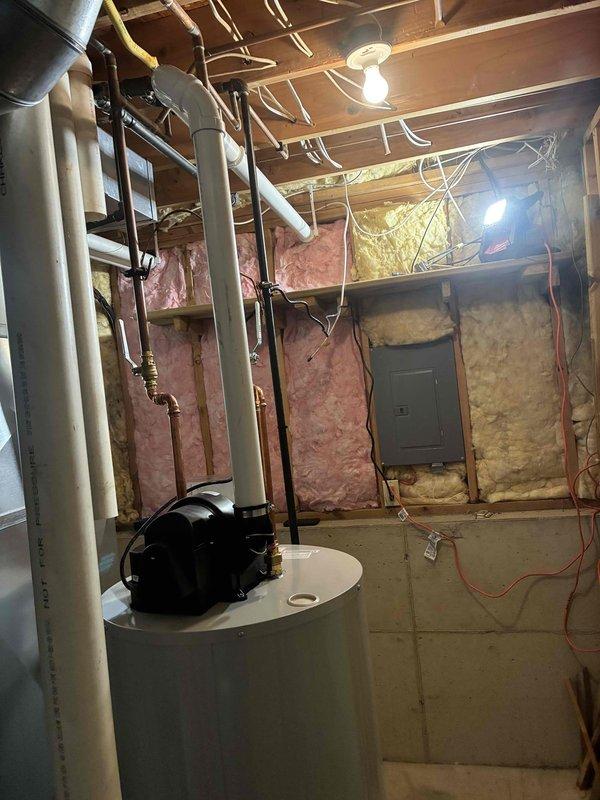 Completed full installation of new HVAC furnace and water heater system in basement utility area. Installed rectangular HVAC unit with metallic finish, connected refrigerant lines along wall studs, and routed silver metallic ductwork from unit. Installed cylindrical water heater with white PVC venting piping, mounted circulator pump on top, and connected all necessary plumbing lines. All systems tested and operational upon completion.