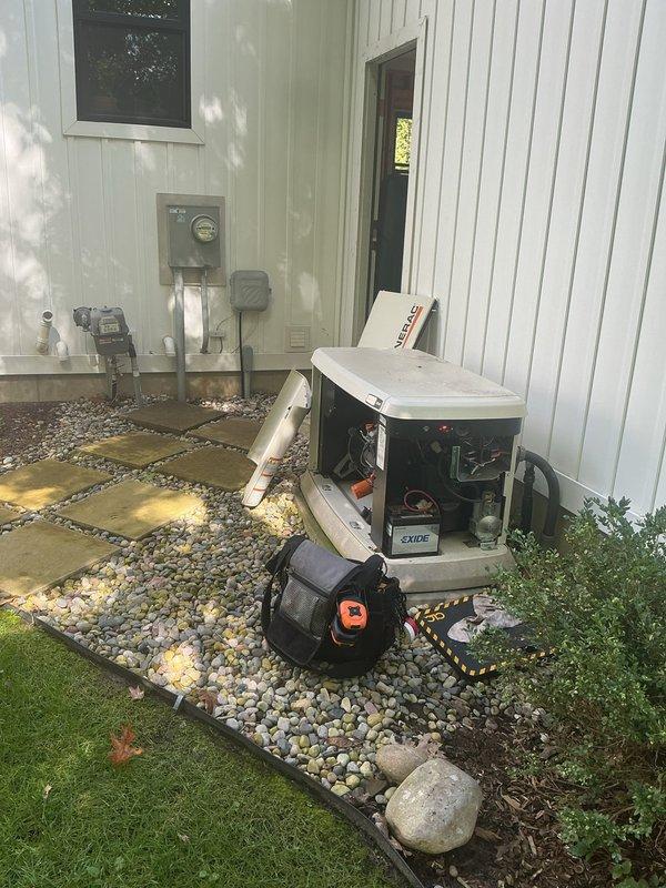 Responded to service call for non-operational backup generator with reported gas odor and exhaust fumes entering furnace intake system. Upon arrival, inspected generator unit positioned on concrete pad adjacent to building exterior and identified improper venting configuration allowing combustion gases to be drawn into nearby HVAC air intake. Documented equipment placement, PVC exhaust piping arrangement, and proximity of furnace intake components. Photographed generator installation showing relationship between exhaust discharge point and building ventilation systems to assess code compliance and safety concerns. Recommended immediate corrective action to separate generator exhaust from furnace intake to prevent carbon monoxide hazard and ensure safe operation of both systems.