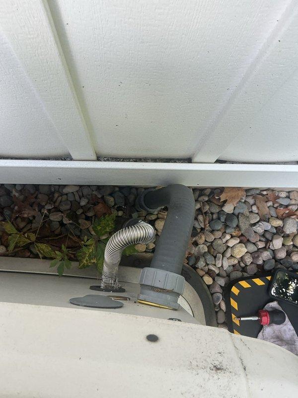 Responded to service call for non-operational backup generator with reported gas odor and exhaust fumes entering furnace intake system. Upon arrival, inspected generator unit positioned on concrete pad adjacent to building exterior and identified improper venting configuration allowing combustion gases to be drawn into nearby HVAC air intake. Documented equipment placement, PVC exhaust piping arrangement, and proximity of furnace intake components. Photographed generator installation showing relationship between exhaust discharge point and building ventilation systems to assess code compliance and safety concerns. Recommended immediate corrective action to separate generator exhaust from furnace intake to prevent carbon monoxide hazard and ensure safe operation of both systems.
