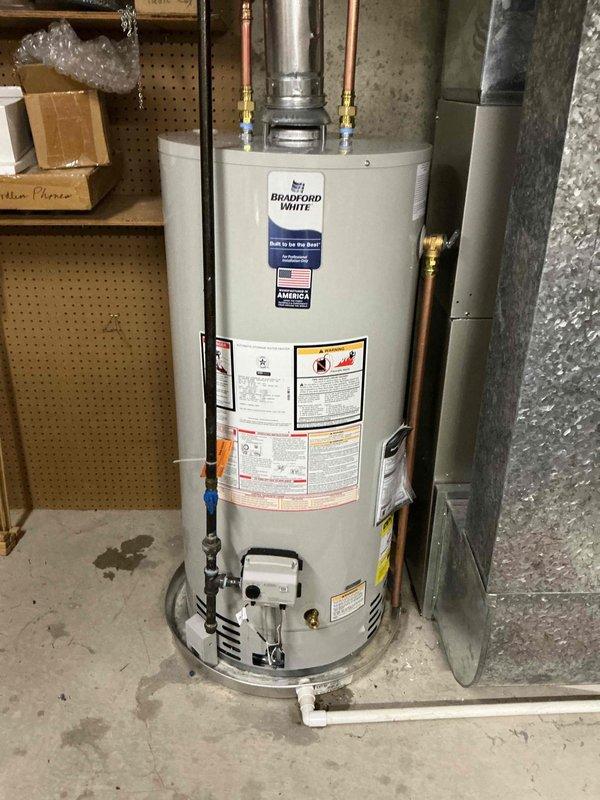 Completed installation of a 40-gallon short natural gas Bradford White water heater in basement utility area. Connected copper supply lines with shut-off valves, installed proper venting system, and verified all connections for safe operation.