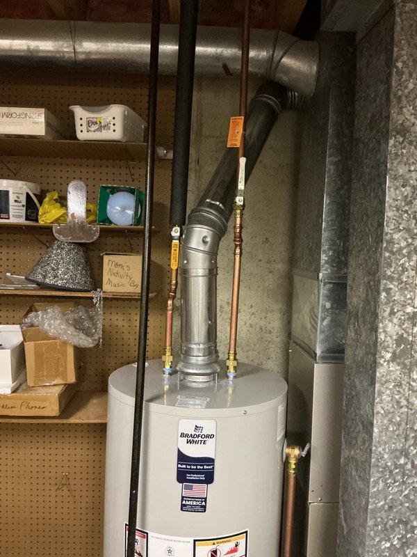 Completed installation of a 40-gallon short natural gas Bradford White water heater in basement utility area. Connected copper supply lines with shut-off valves, installed proper venting system, and verified all connections for safe operation.