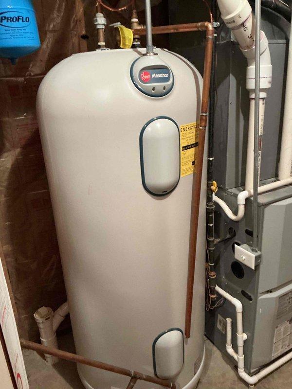Conducted tankless water heater estimate for customer inquiring about current promotional offering. Assessed existing installation consisting of Rheem Marathon electric water heater in unfinished basement utility area with exposed framing, copper supply lines, and adjacent HVAC system. Documented current equipment configuration, plumbing connections, and available space for potential tankless unit installation, capturing details of water treatment system, electrical access, and venting requirements for conversion feasibility.