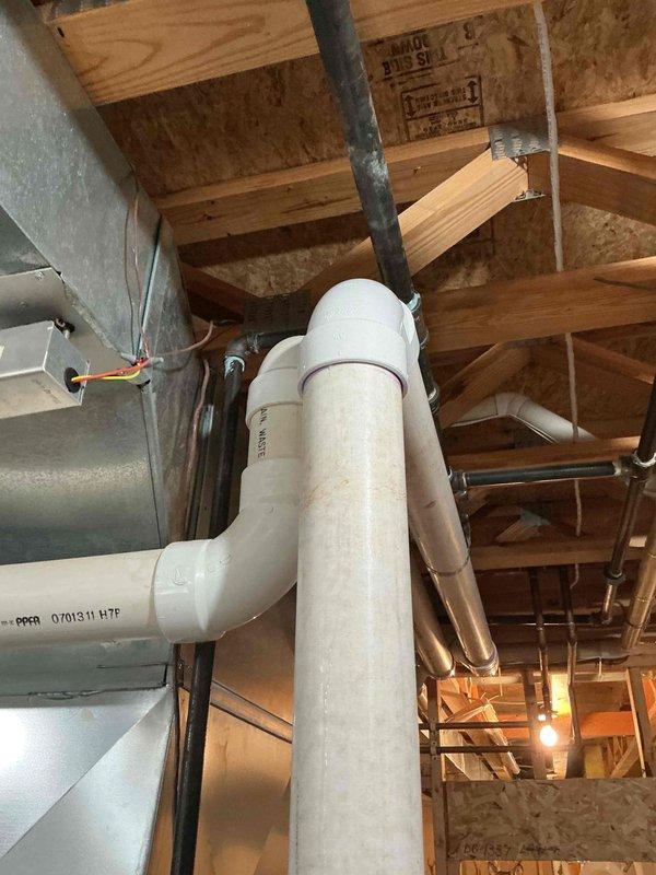Responded to water leak concern related to furnace condensation on floor. Upon inspection, identified PVC condensate drain piping in basement showing water staining and mineral deposits on exterior surfaces. Verified drainage system components including vertical waste pipes and elbow fittings for proper operation. Documented conditions with photographs showing discoloration on PVC piping and surrounding basement infrastructure. System evaluated to ensure condensate drainage functioning as designed with no immediate concerns requiring repair.