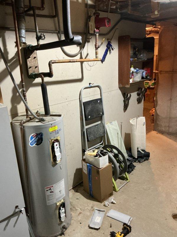 Responded to no hot water call for tank-type water heater in basement utility area. Upon arrival, found unit to be approximately 15+ years old, predating customer's 2012 occupancy. Performed diagnostic inspection of water heater and associated plumbing connections, including examination of gas supply lines, water inlet/outlet piping, temperature and pressure relief valve, and electrical components. Noted this unit differs from the Bradford White model previously on file in system records. Documented equipment condition and configuration with photographs showing copper supply piping, black insulated lines, and overall installation layout. Verified electrical panel location around corner from water heater for reference. Unit assessed as aged beyond typical service life expectancy for residential tank water heaters.
