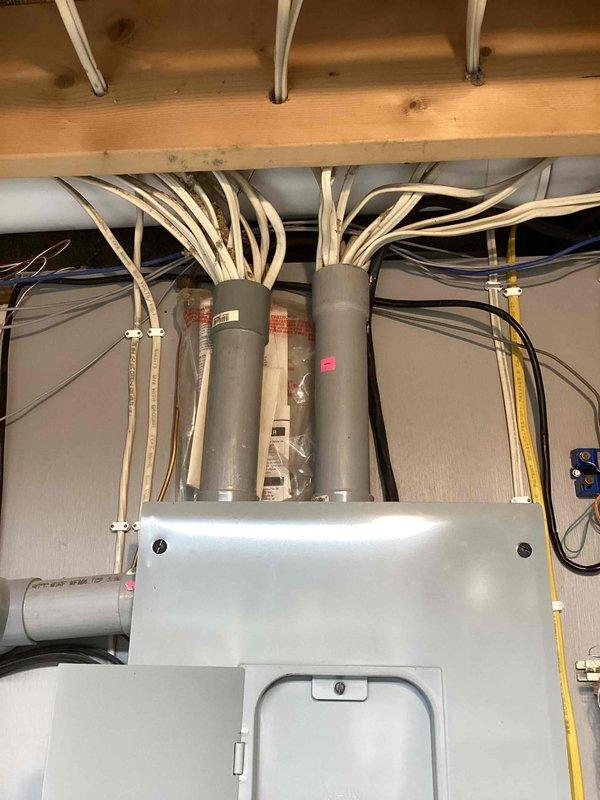 Completed generator estimate and furnace tune-up on a 7-year-old heating system. Documented existing HVAC ductwork installation in attic space, including gray cylindrical supply ducts, flexible duct branches, and metal plenum with access panel. Photographed electrical panel configuration showing main breaker panel with dual rows of circuit breakers, associated sub-panels, and integrated communication equipment for comprehensive system assessment.