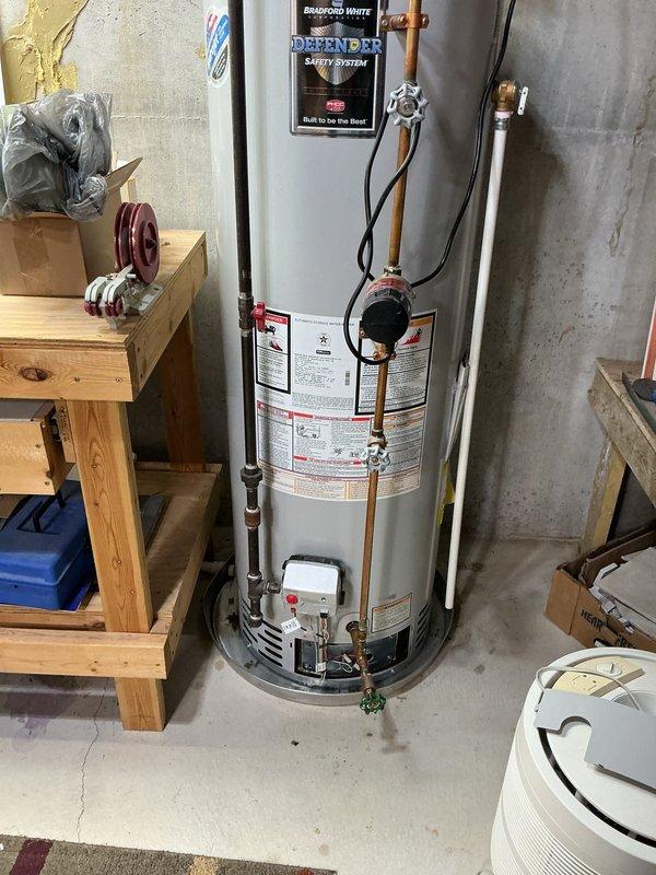 Responded to service call for leaking 12-year-old Bradford White water heater with Defender Safety System. Upon inspection, identified active leak and documented condition of unit and surrounding plumbing connections including copper supply lines, brass fittings, and pressure relief valve. Based on age of equipment and observed conditions, provided assessment and recommendations to customer.