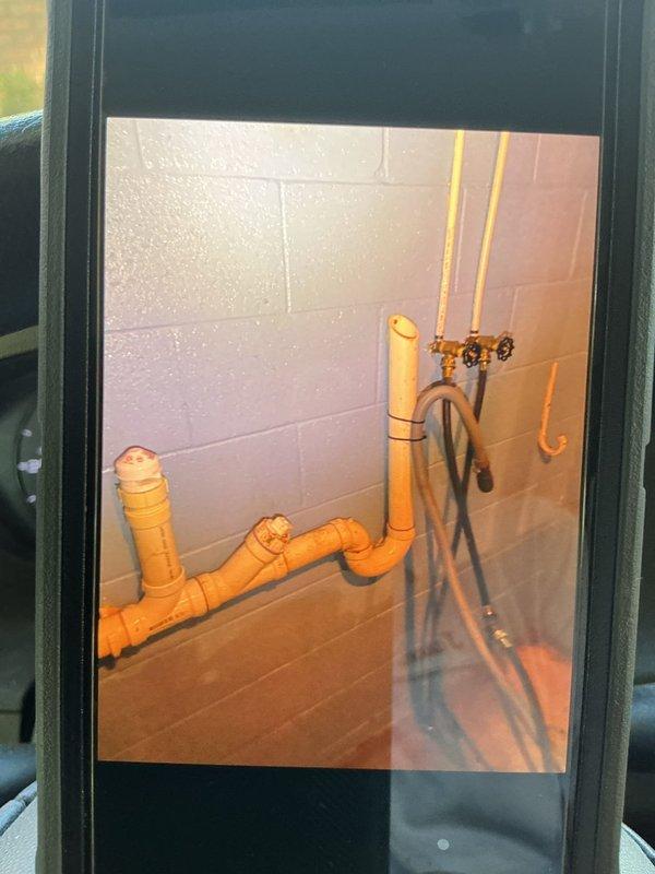 Responded to basement washing machine standpipe overflow caused by drainage blockage. Upon arrival, located affected standpipe behind washing machine in basement area with visible water damage from recent overflow. Inspected drainage system including visible PVC drain lines and associated plumbing connections. Identified blockage in standpipe preventing proper drainage during washing machine discharge cycle. Utilized appropriate drain cleaning equipment to clear obstruction from standpipe and restore proper flow. Tested system by running water through drain line to verify complete clearance and proper drainage function. Confirmed standpipe now draining freely with no backup or slow drainage issues. Photographed existing plumbing configuration including gas lines, drain lines, and ejector pump system for service records. Advised property owner on proper maintenance practices to prevent future blockages.