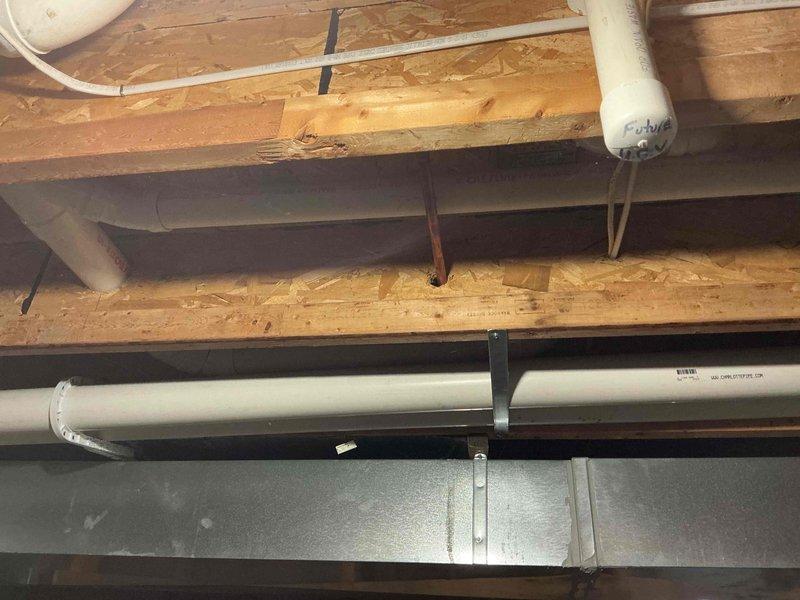 Responded to recurring kitchen sink backup issue. Inspected drain piping infrastructure in basement ceiling area, verifying horizontal PVC drain line pitch and proper installation of drainage system components. Confirmed drain line slope using level to ensure adequate gravity flow. Examined pipe support brackets, connections, and overall system configuration to identify potential causes of repeated backup problems. Documented existing plumbing installation with photos showing horizontal drain runs, pipe supports, and relationship to floor joists for further evaluation of drainage concerns.