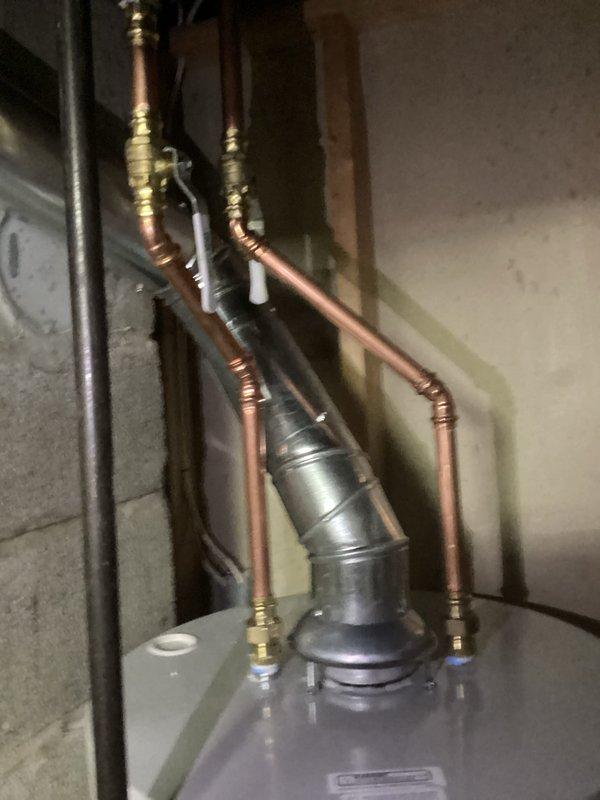 Successfully installed a 40-gallon natural draft natural gas water heater (short tank model, 48 1/16" height) in basement utility area. Connected all copper supply lines with brass fittings and unions, installed PVC venting system, and integrated unit with existing plumbing infrastructure including gas line connections. Installation includes 6-year parts and 1-year labor warranty coverage.
