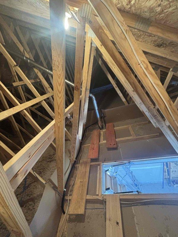 Successfully installed a new unit heater system in the attic space. Installation included mounting the unit heater between floor joists, running electrical wiring (black and white conductors) through the wall cavity to power the unit, and connecting necessary ductwork with flexible ducting routed through the attic structure. Applied spray foam insulation at penetration points to seal gaps and prevent air leakage around the installation area. All work completed to manufacturer specifications with proper electrical connections and structural support utilizing existing roof trusses and floor joists.