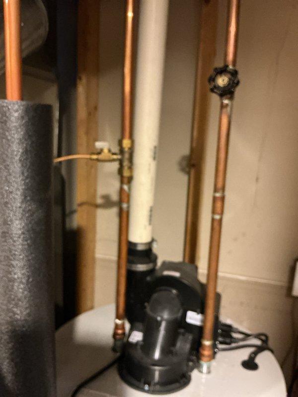 Responded to emergency call for loud explosion sound from water heater with water detected in drain pan. Inspected 16-year-old water heater system and associated plumbing connections. Evaluated condition of copper supply lines, PVC venting configuration, and recirculation pump assembly. Documented existing installation including hot and cold water connections, brass shut-off valves, and mechanical room setup. Photographed HVAC ductwork proximity, pipe routing, and overall system layout. Provided estimate for water heater replacement due to age and reported failure symptoms consistent with tank rupture.