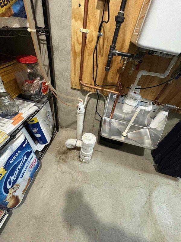 Responded to plumbing leak located at main water meter assembly before the house shut-off valve. Coordinated water shut-off at street level to facilitate repair. Inspected copper piping connections on both sides of the meter and identified source of minor leak at fitting. Repaired compromised connection, restored water service, and verified system integrity with no active leaks present upon completion. Documented existing plumbing configuration including ball valve with yellow handle, water meter with protective cap, and copper supply lines showing age-related patina.